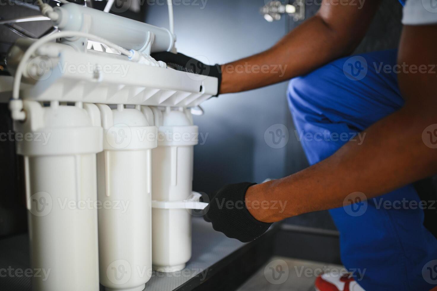Plumber installs or change water filter. Replacement aqua filter. Repairman installing water filter cartridges in a kitchen. photo