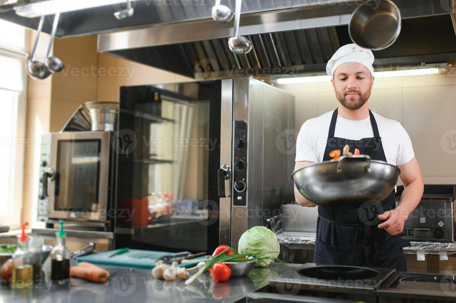 Chef cook in uniform cooking in the big cooker at the restaurant kitchen photo