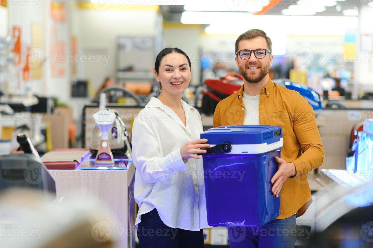 A young couple buys a portable refrigerator in an electronics store photo