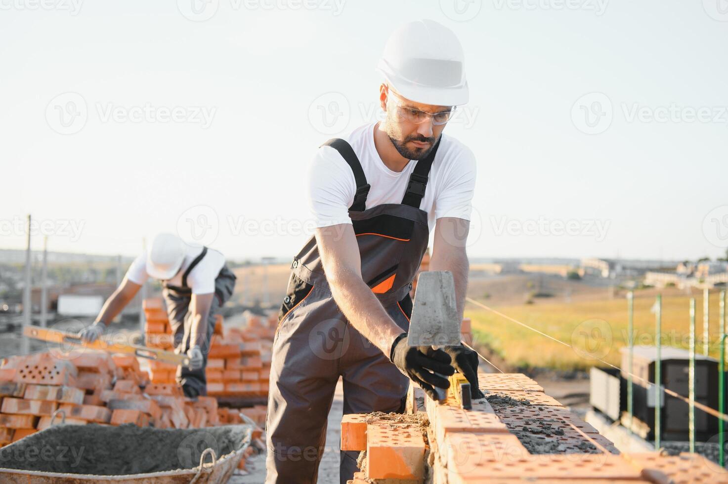 Construction worker man in work clothes and a construction helmet. Portrait of positive male builder in hardhat working at construction site photo