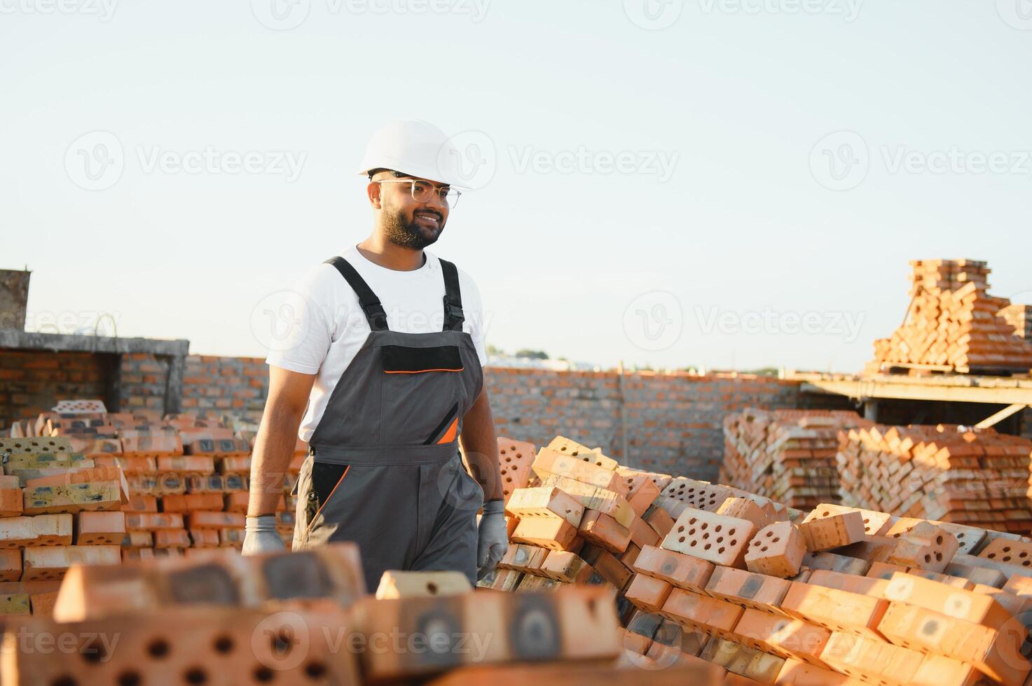 Portrait of an Indian construction worker in overalls and a hard hat at a construction site photo