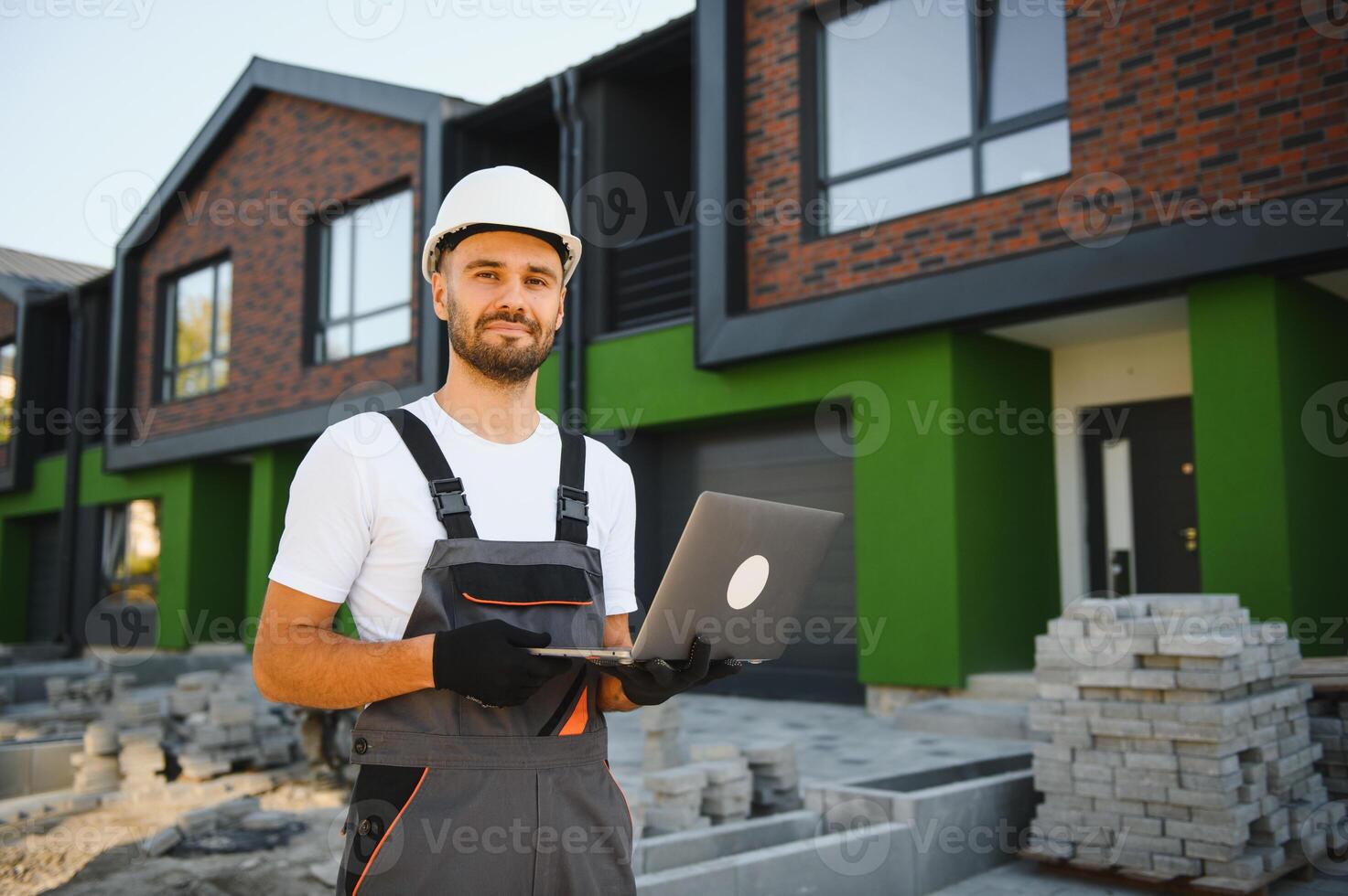 Joyful building site manager inspecting new cottage complex photo