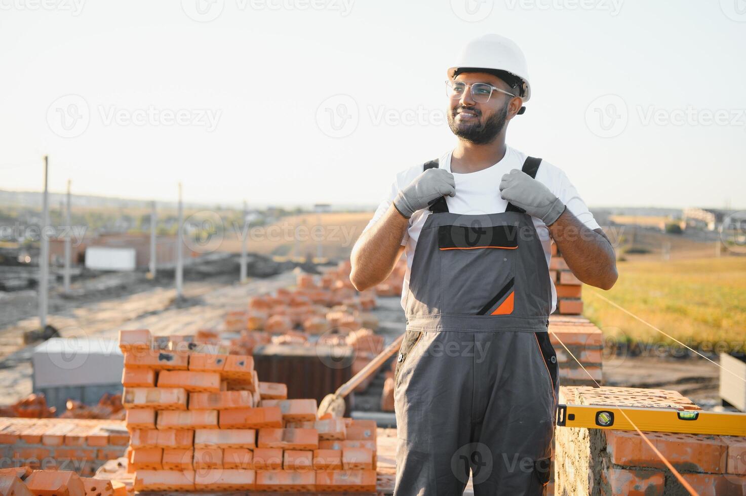 Installing brick wall. Indian Construction worker in uniform and safety equipment have job on building photo