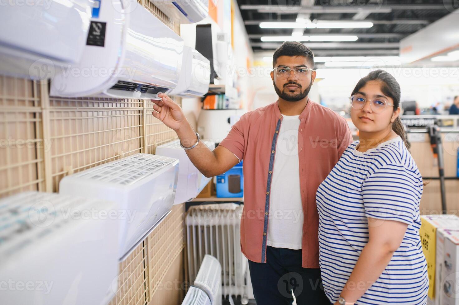 A beautiful indian couple chooses an air conditioner at home in an electronics store. photo