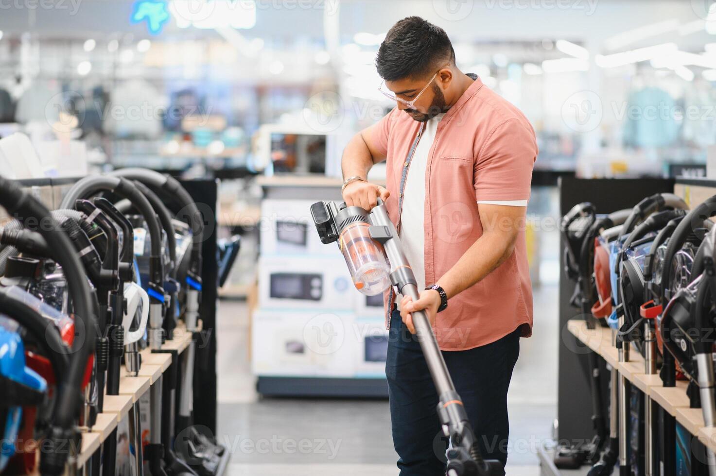 An Indian man is choosing a new vacuum cleaner in an electronics store photo