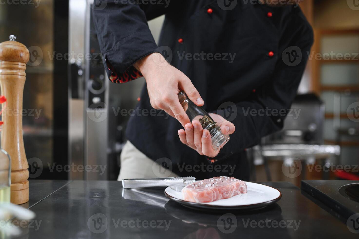 Closeup of a concentrated male chef garnishing food in the kitchen photo