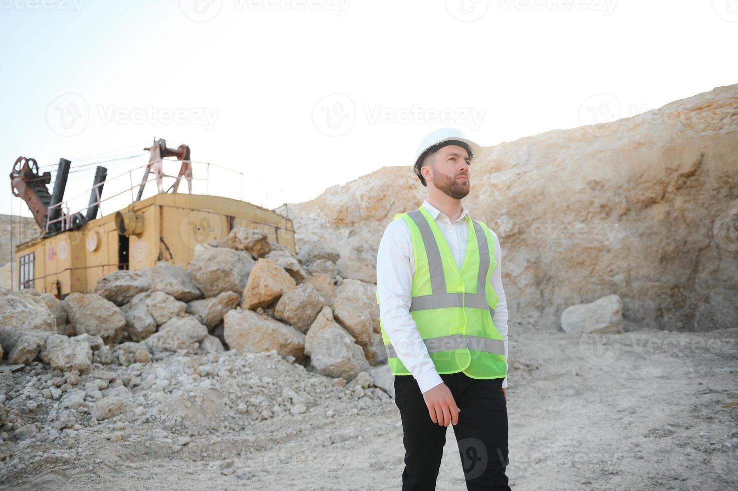 Worker in hardhat standing in stone quarry photo