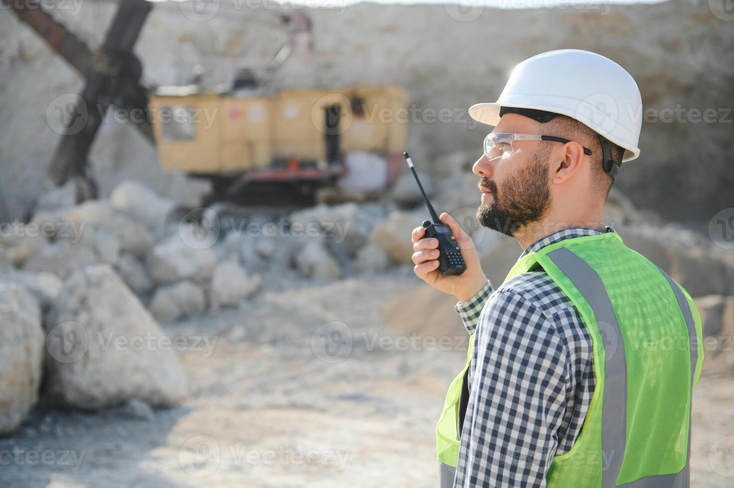 Worker in hardhat standing in stone quarry photo