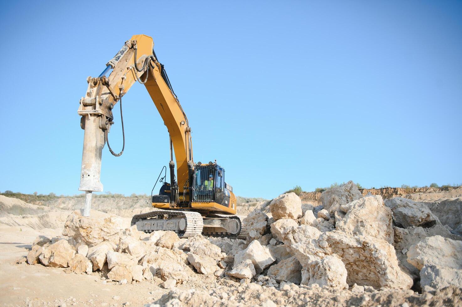 Hydraulic breaker hammer in a quarry for limestone mining with an excavator photo