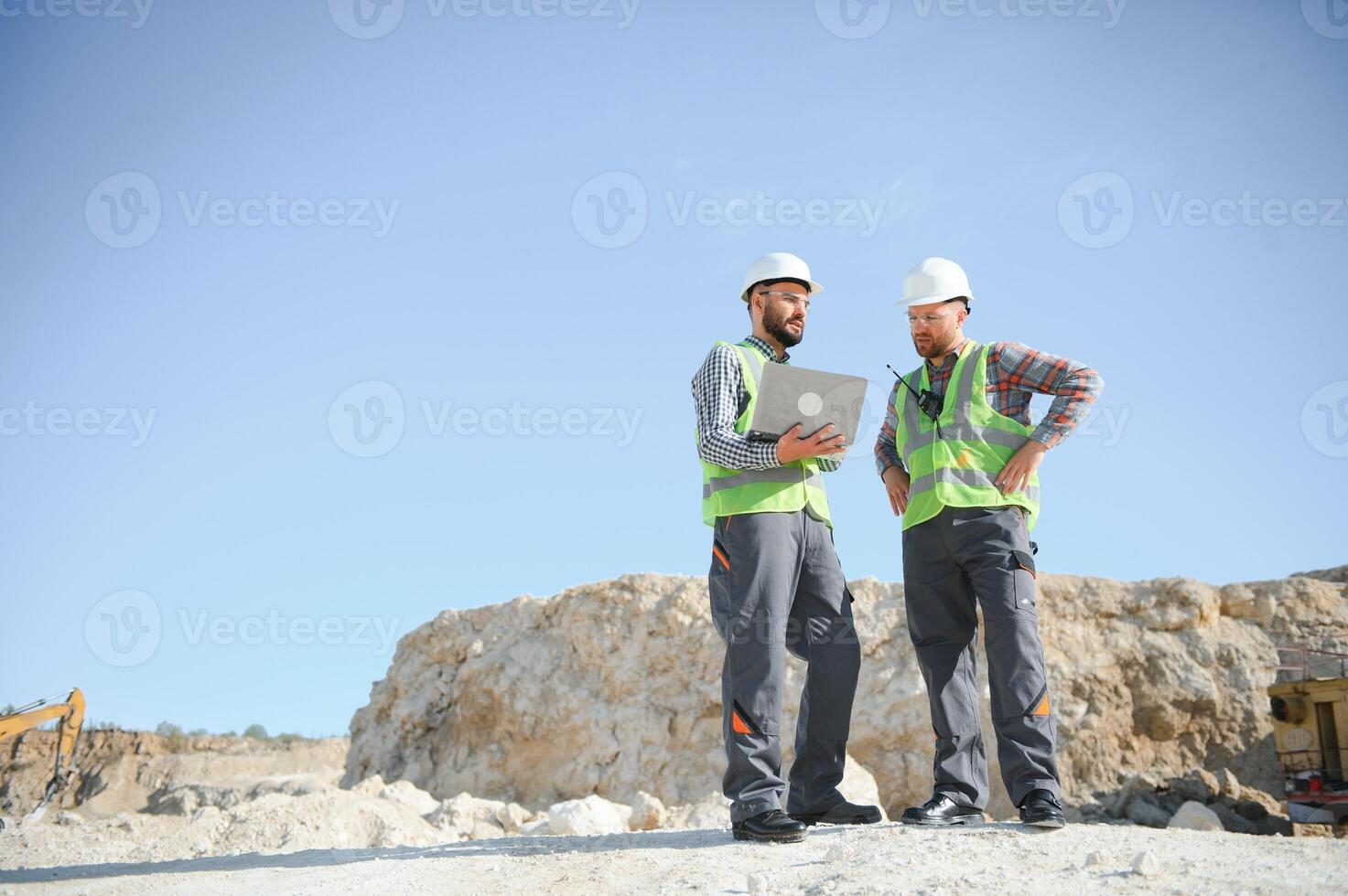 Portrait of stone quarry workers standing on the background of an excavator photo