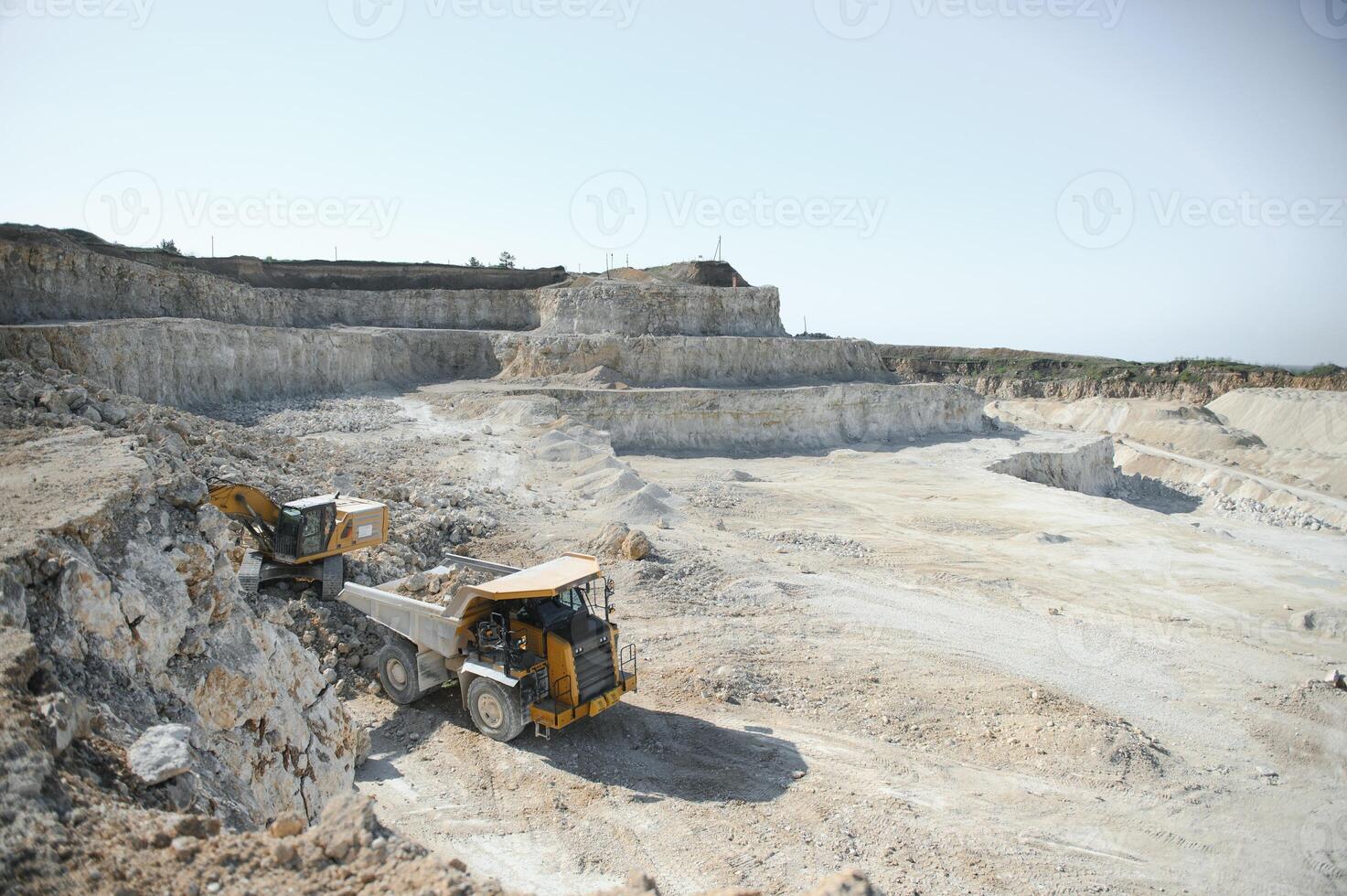 Large quarry dump truck. Big yellow mining truck at work site. Loading stone into body truck photo