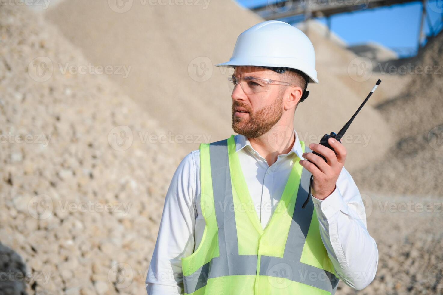 A worker in a helmet stands at a stone crushing plant photo