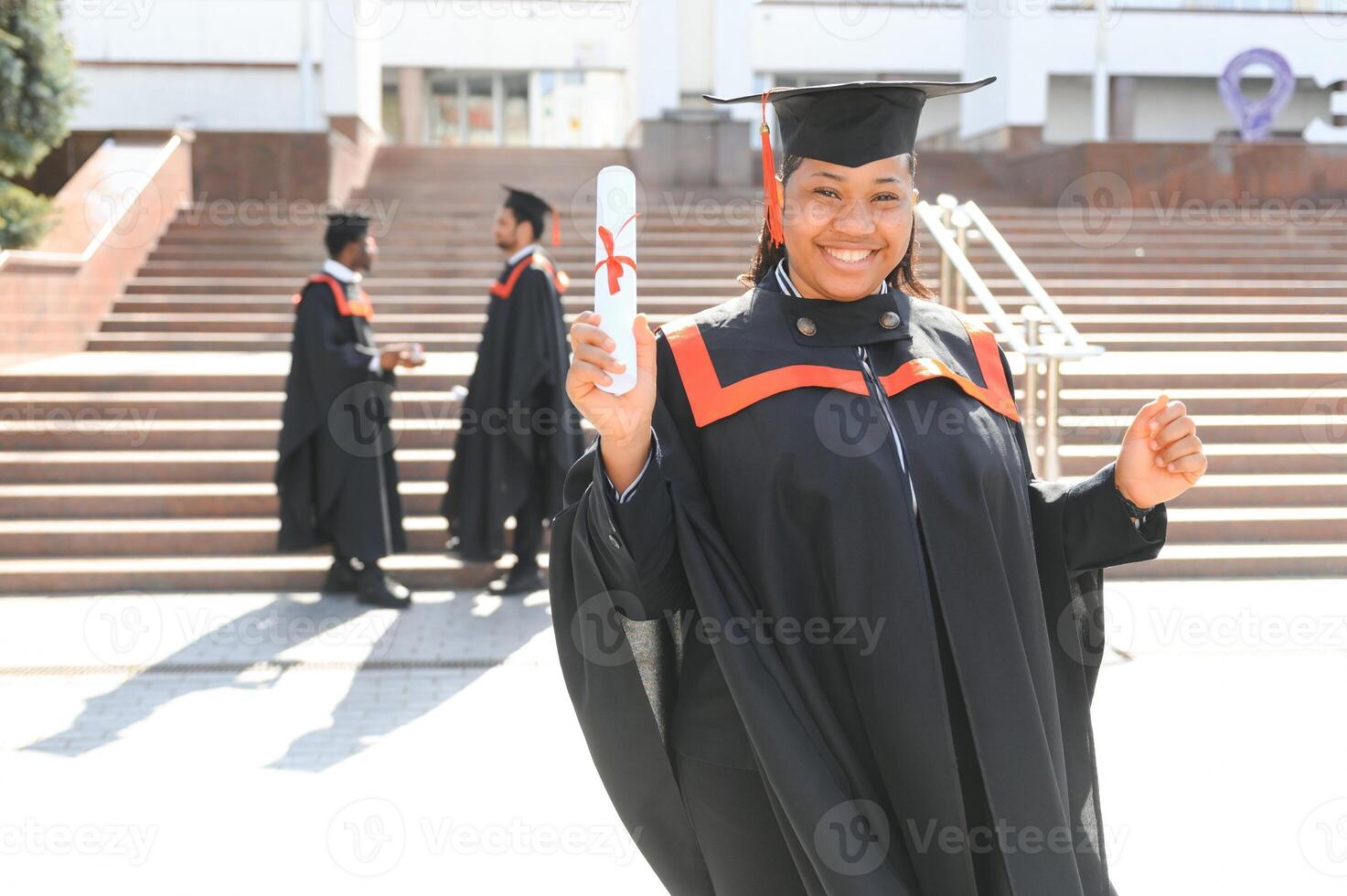 pretty african female college graduate at graduation with classmates photo