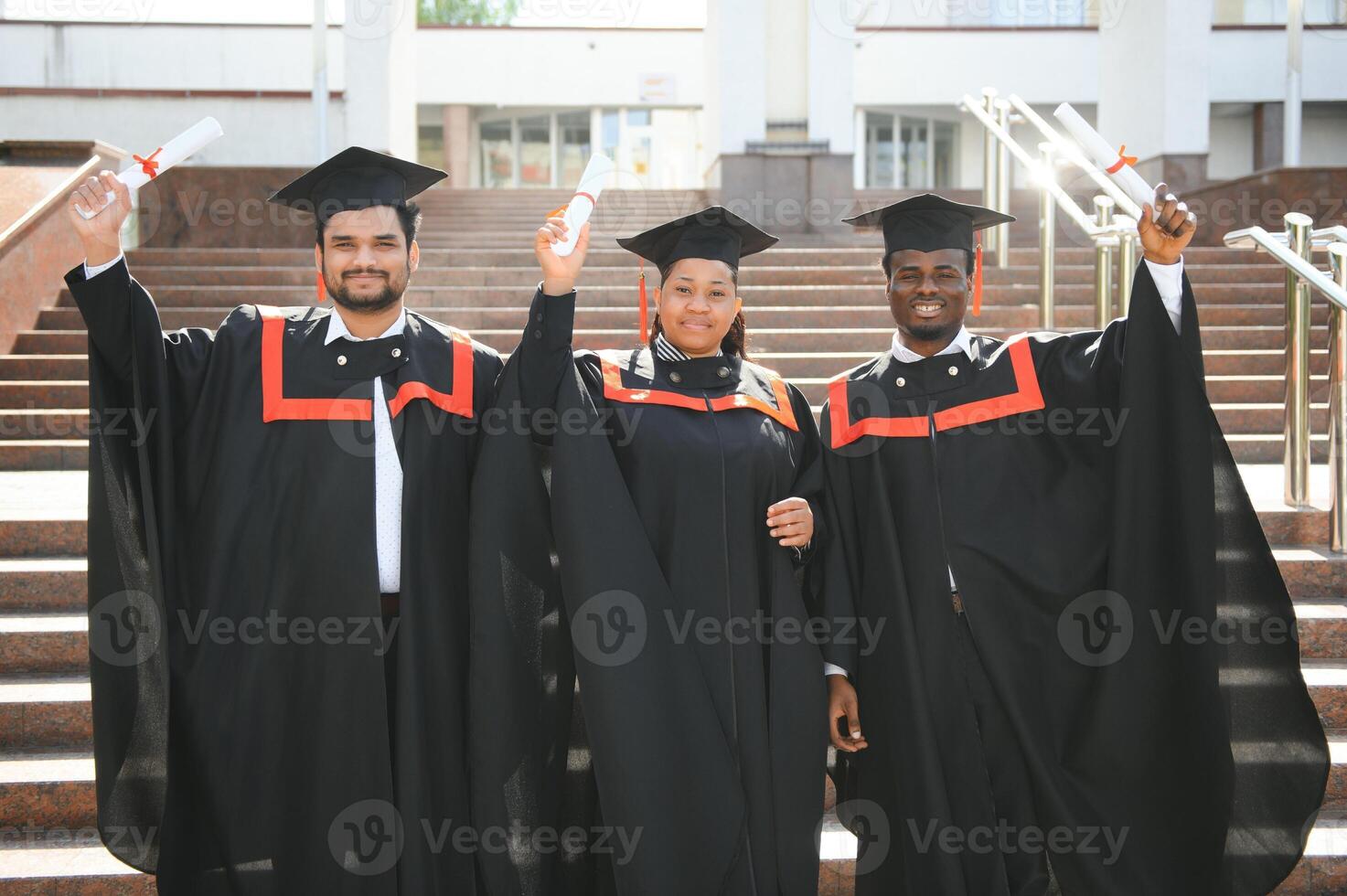 education, graduation and people concept - group of happy international students in mortar boards and bachelor gowns with diplomas photo