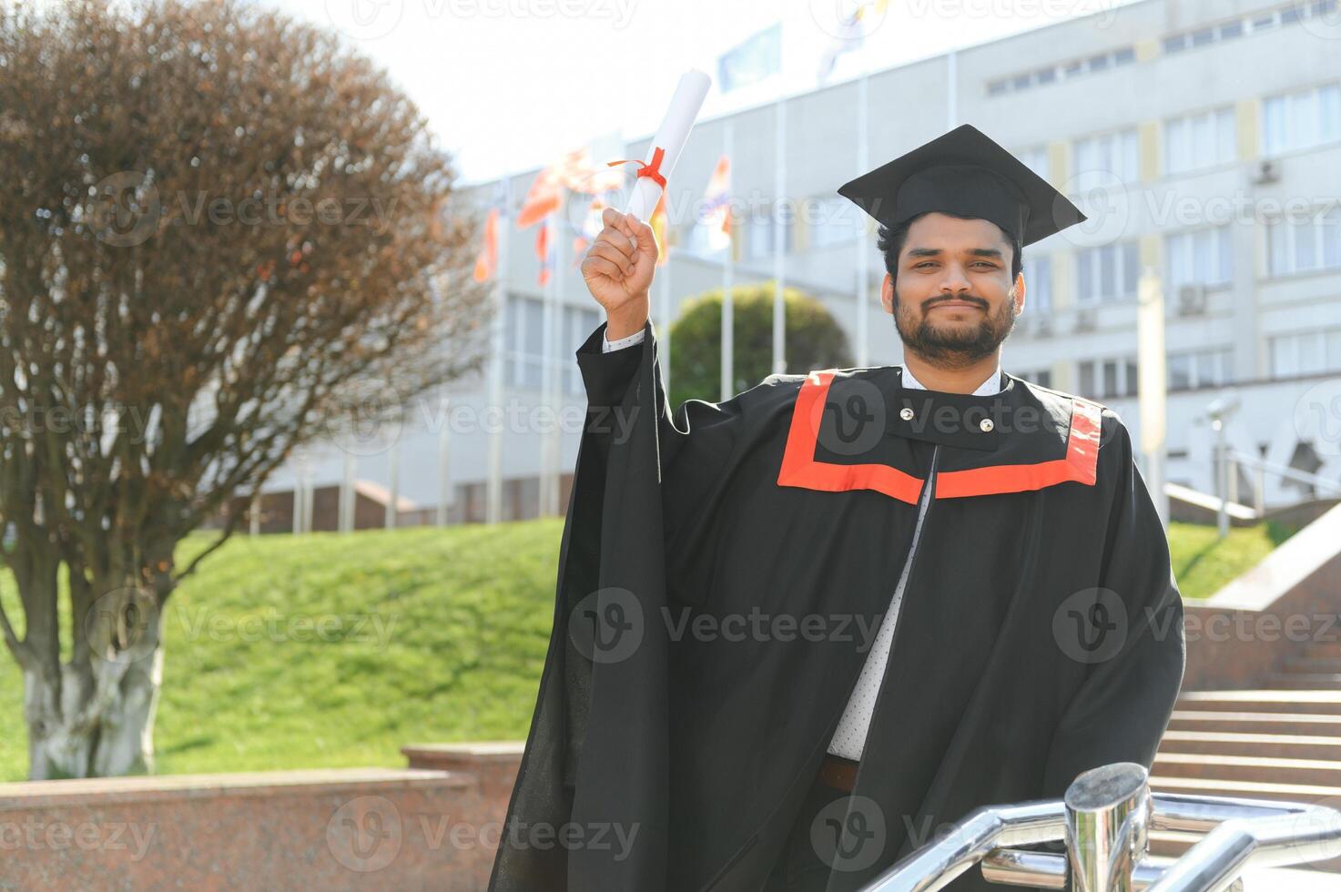 Handsome indian graduate in graduation glow with diploma photo