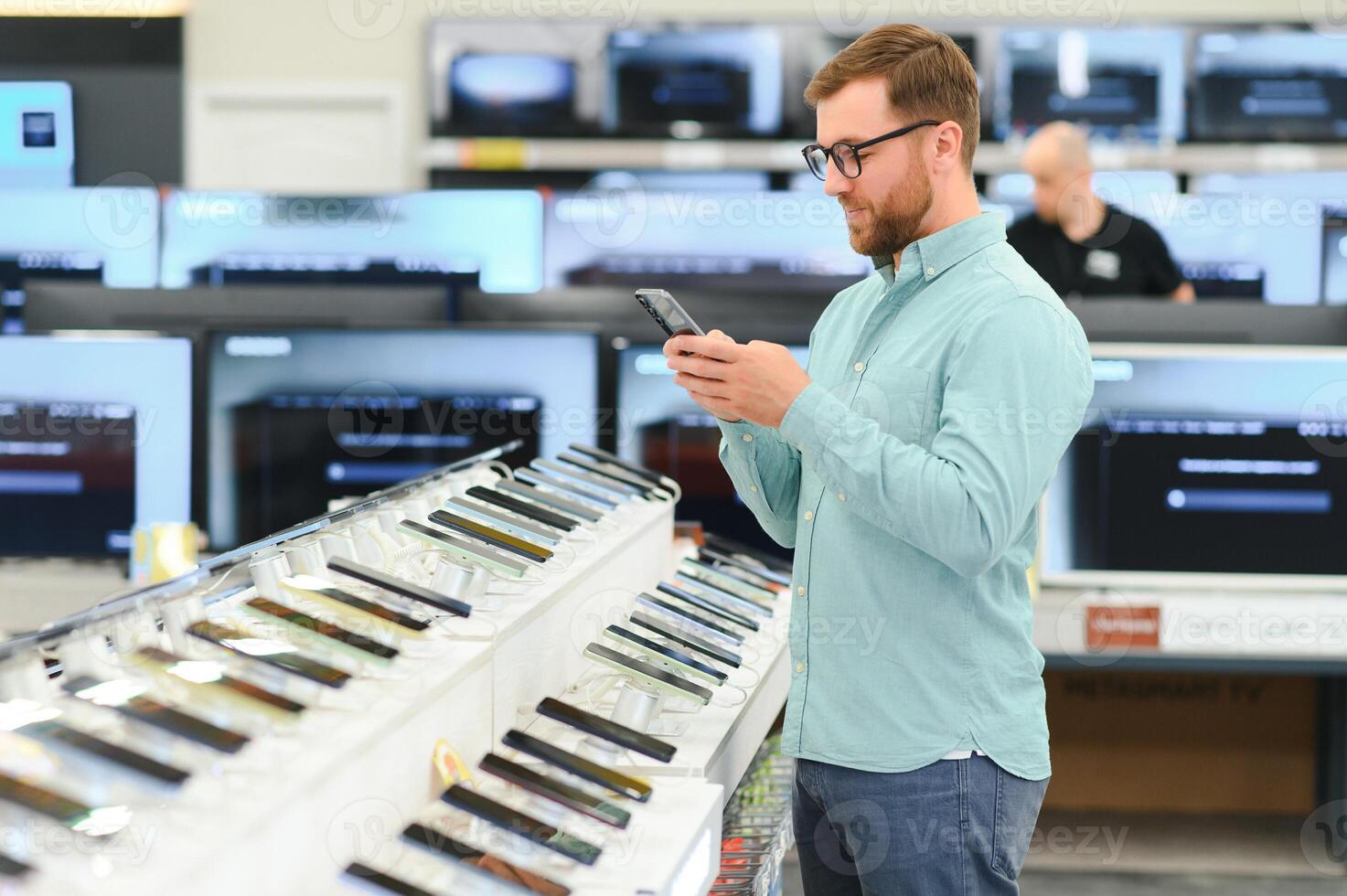 Happy man chooses mobile phone in electronics store photo
