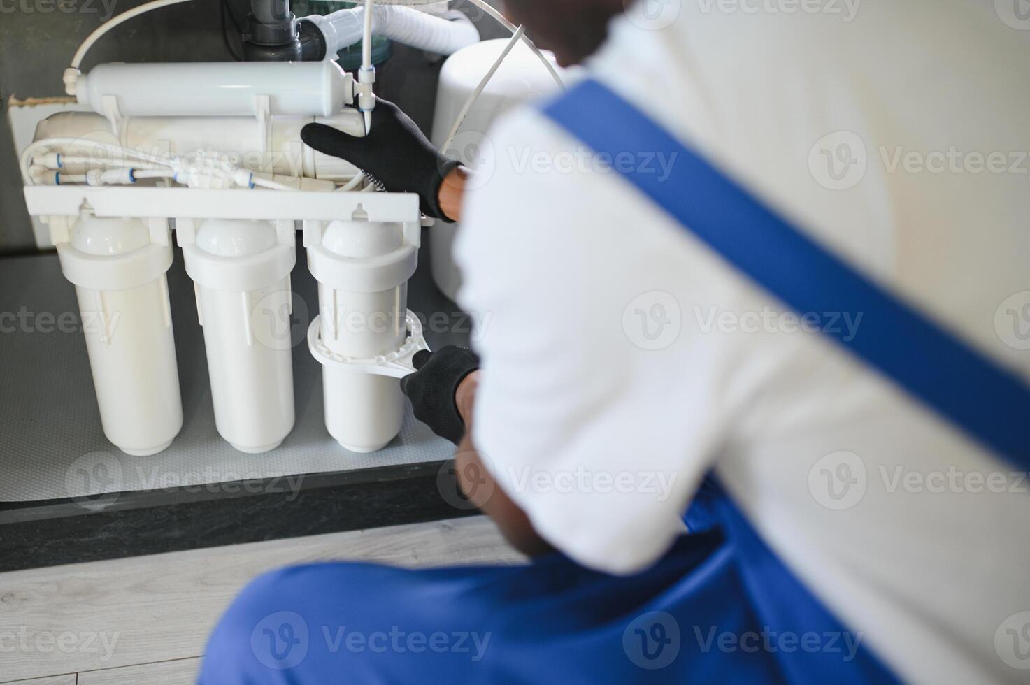 Plumber installs or change water filter. Replacement aqua filter. Repairman installing water filter cartridges in a kitchen. photo