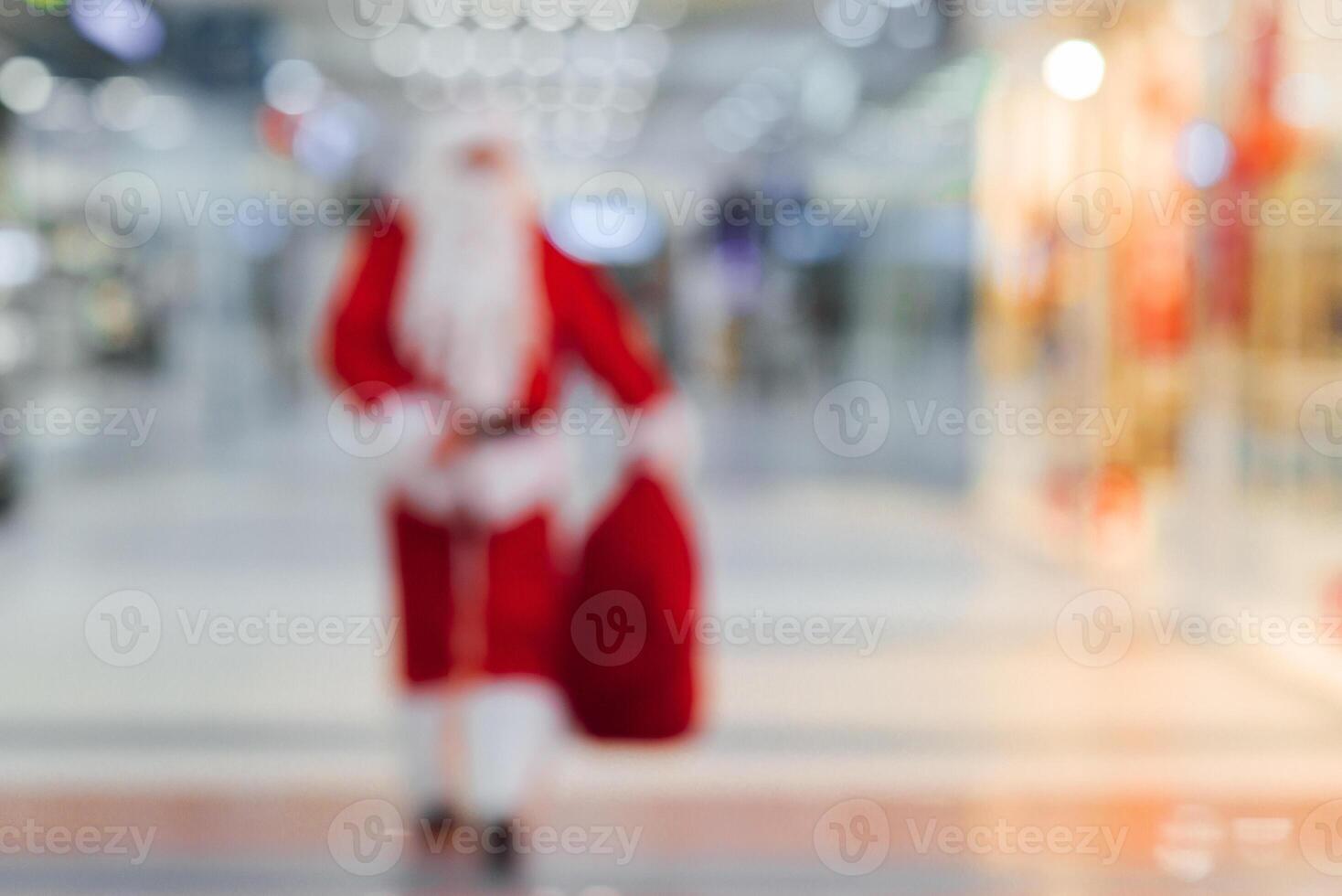 Blurred Santa Claus near the tree in the lobby of shopping center photo
