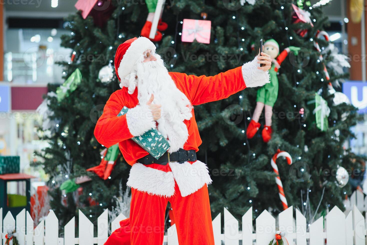 Santa Claus the background of the Christmas tree in the lobby of the modern shopping mall. photo