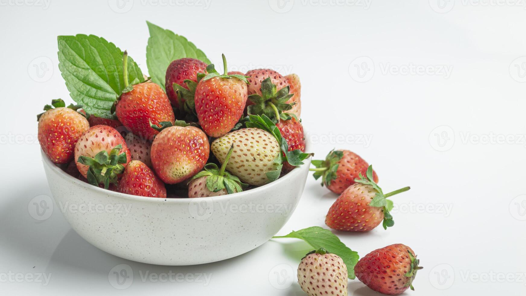 a bowl of strawberries with leaves on top photo
