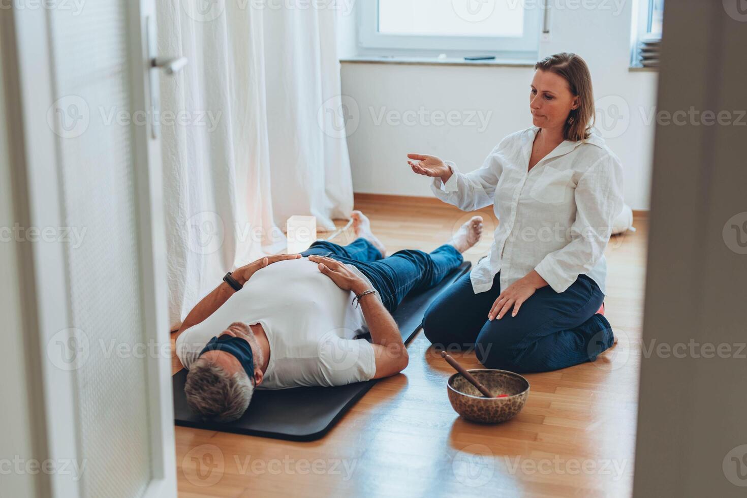 Man and woman practicing mindful breathing together during a meditation session,seated on mats with sound bowls photo