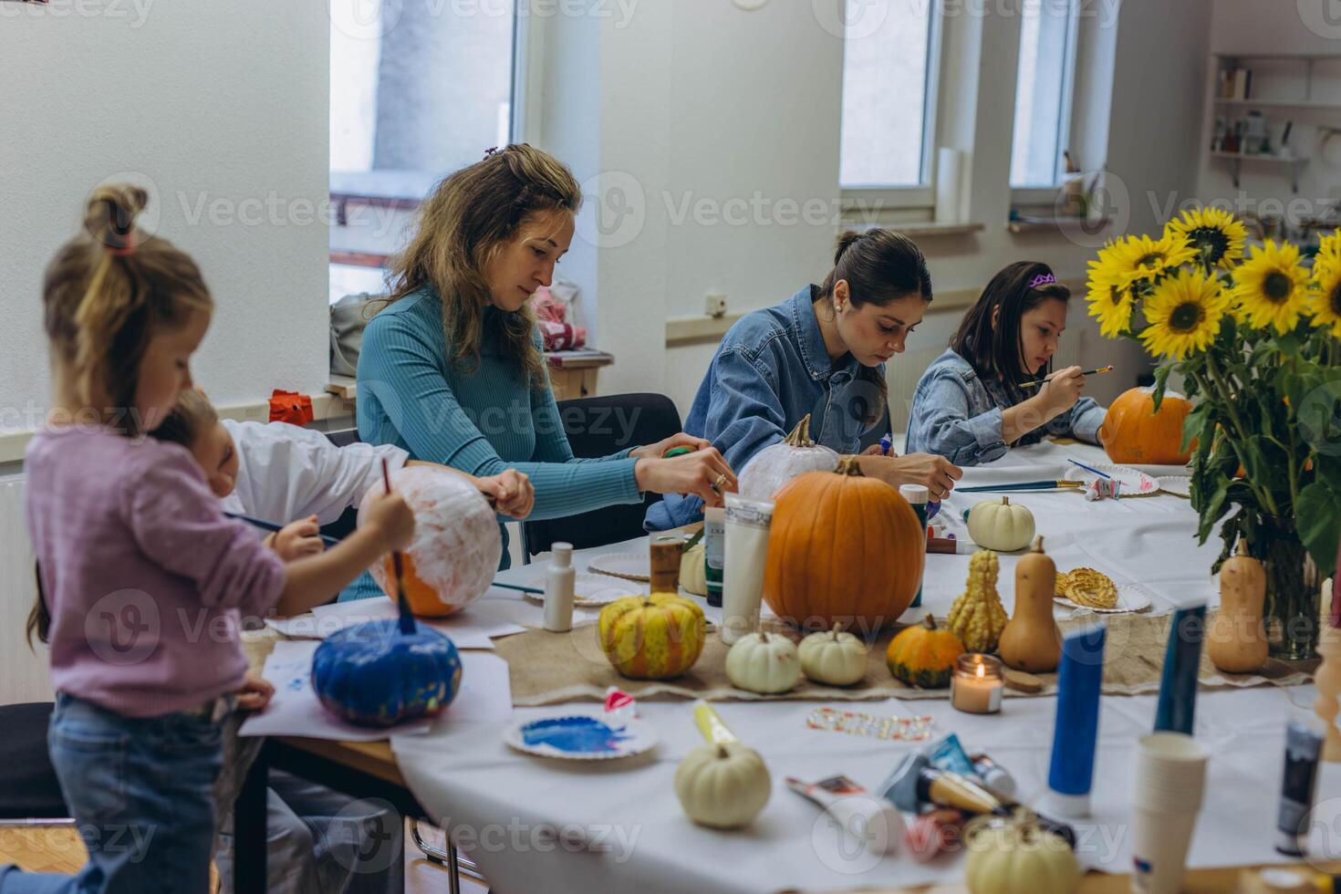 Children and adults painting pumpkins for Halloween, enjoying a fun and creative activity together. photo
