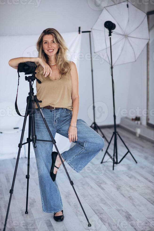 The photo shows a female photographer working in a studio environment.