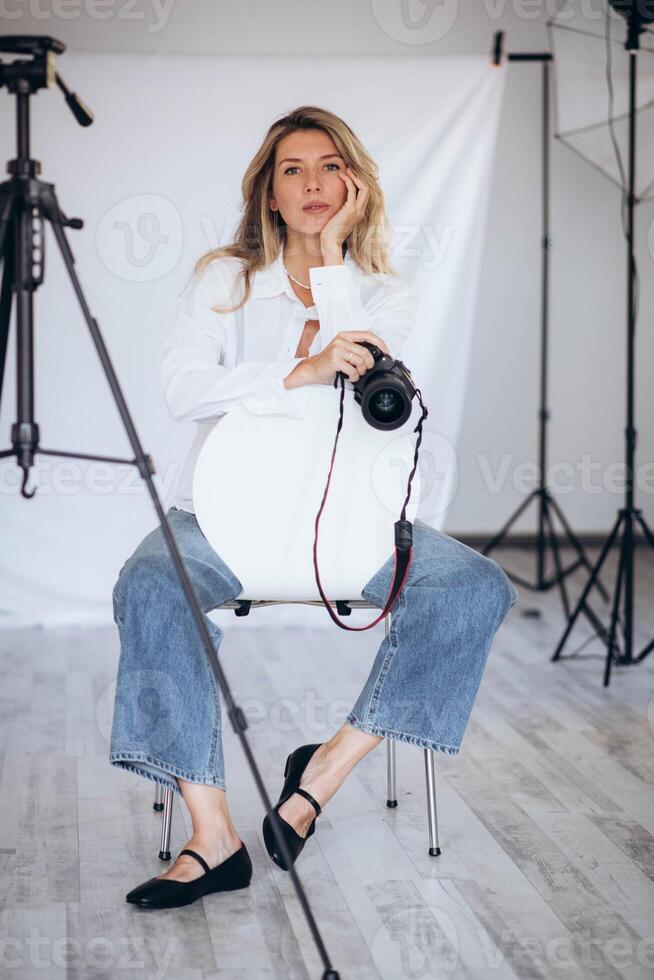 Female photographer in a modern studio, confidently holding a camera. The lighting and composition create a strong image of creative empowerment. photo