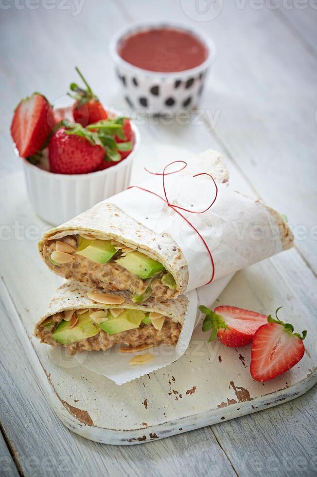 Avocado wrap roll with strawberry on a wooden chopper wallpaper photo