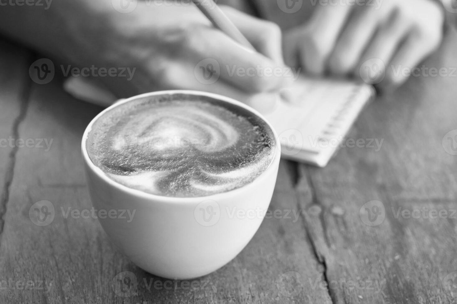 A person writing in a notebook with a cup of coffee photo