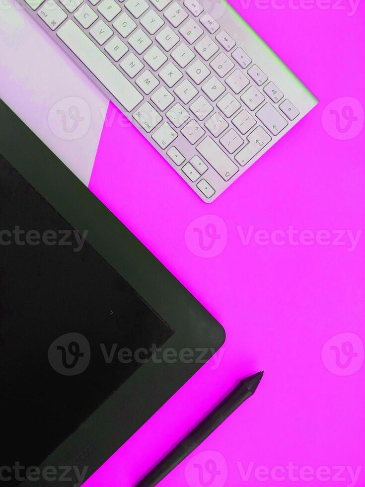 A keyboard, mouse, and tablet on a pink background photo