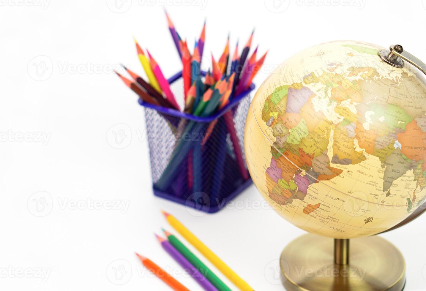 Focus globe and blur crayon or colored pencils behind in box on white background. Learning, study and education concept. photo