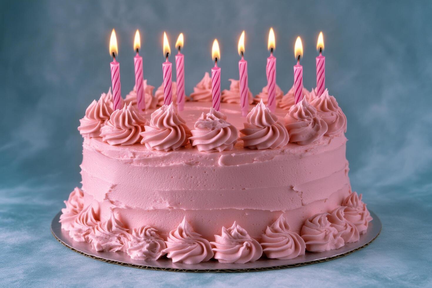 A colorful pink birthday cake with candles and sprinkles set against a bright blue background photo