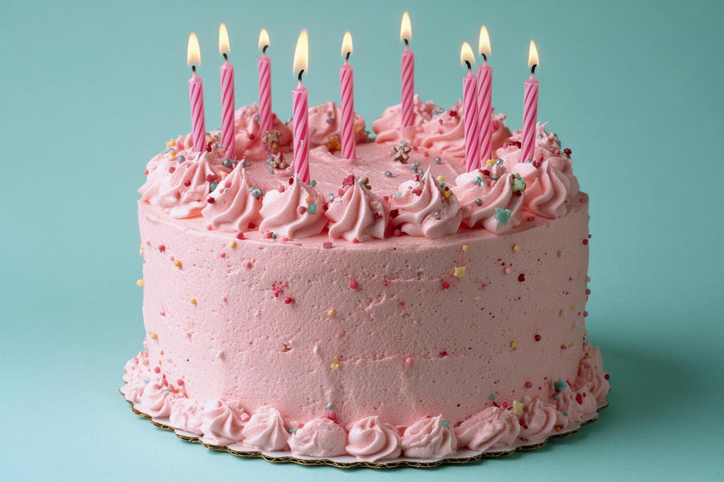 A colorful pink birthday cake with candles and sprinkles set against a bright blue background photo