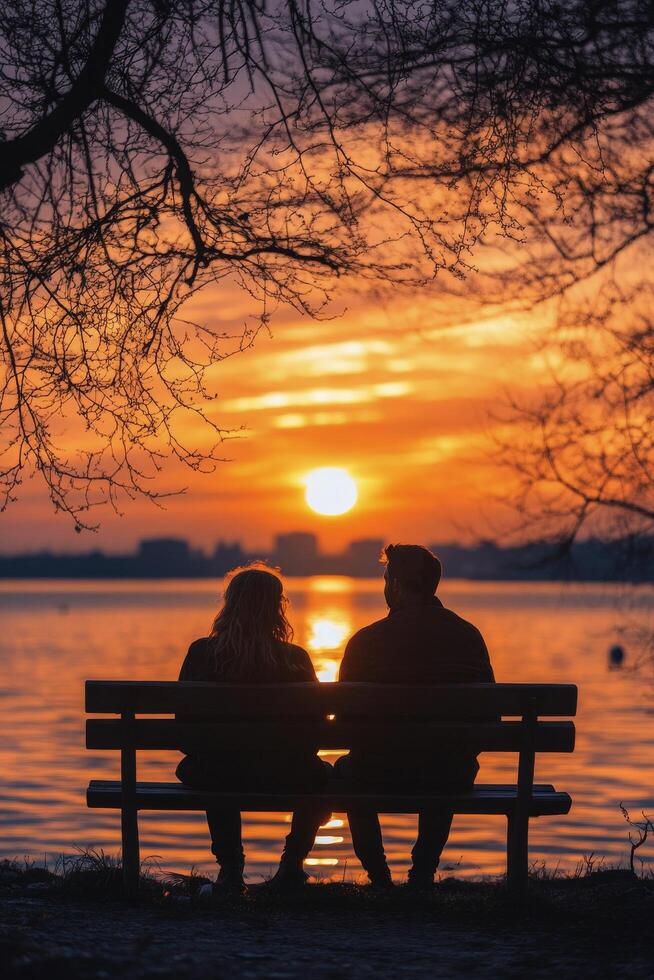 Couple enjoying a sunset while sitting on a bench in a peaceful park during autumn evening photo