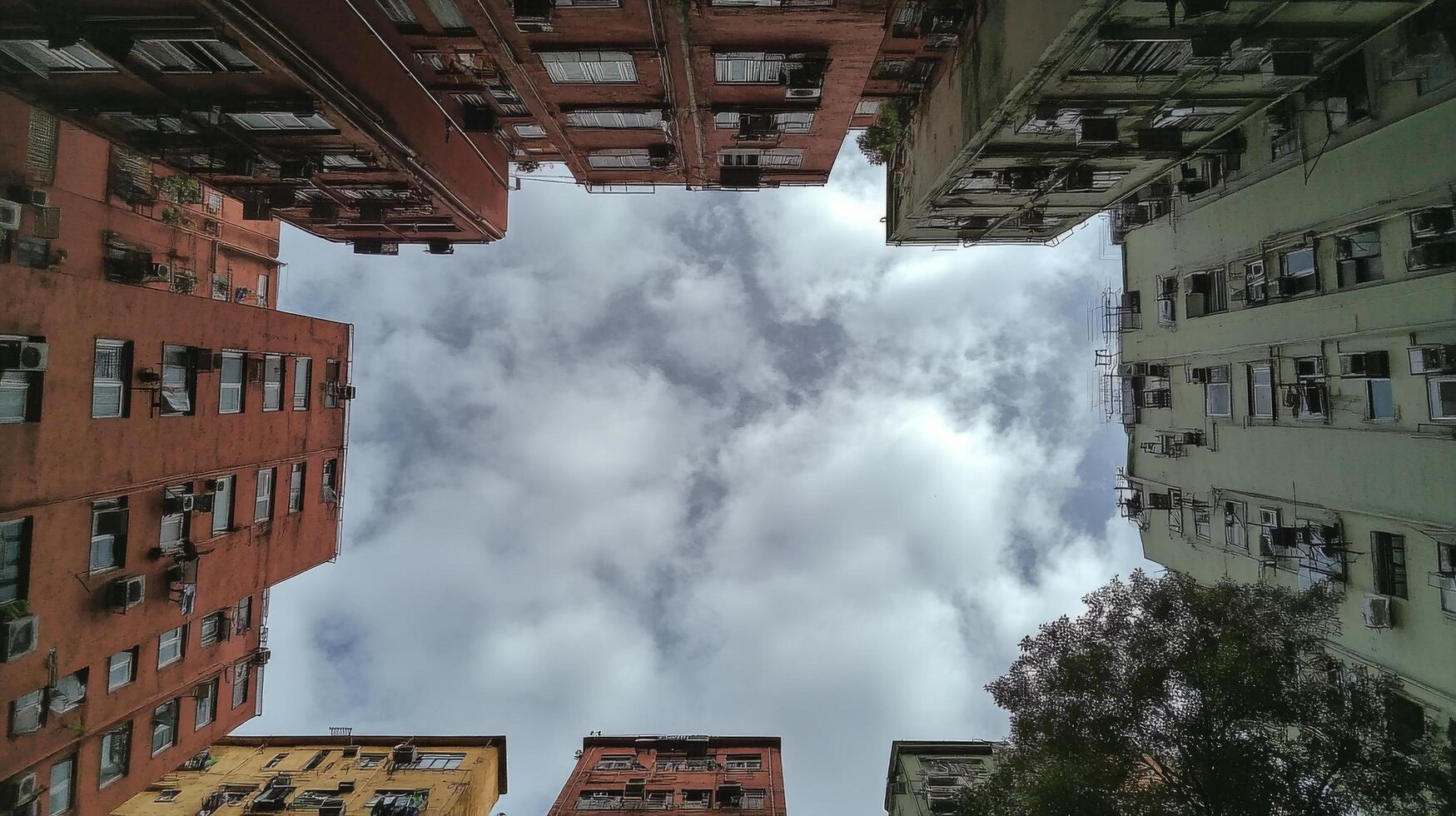 Looking up at a vibrant urban alleyway surrounded by historic buildings and cloudy sky photo