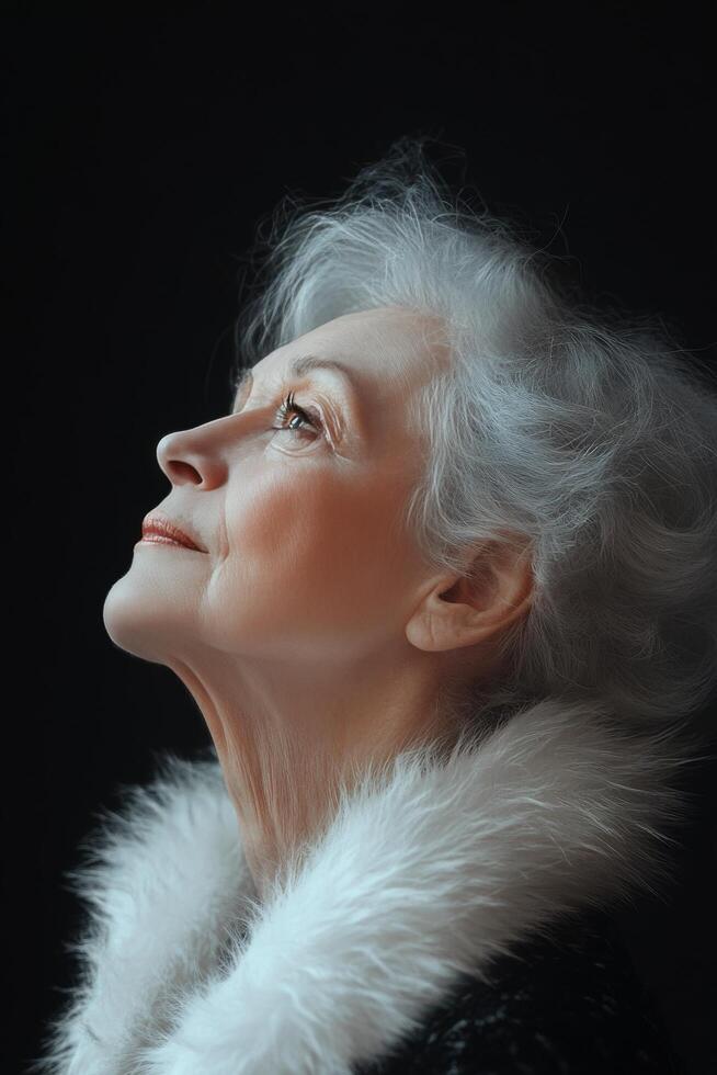 Elderly woman gazing thoughtfully with grey hair and a fur collar in soft light photo