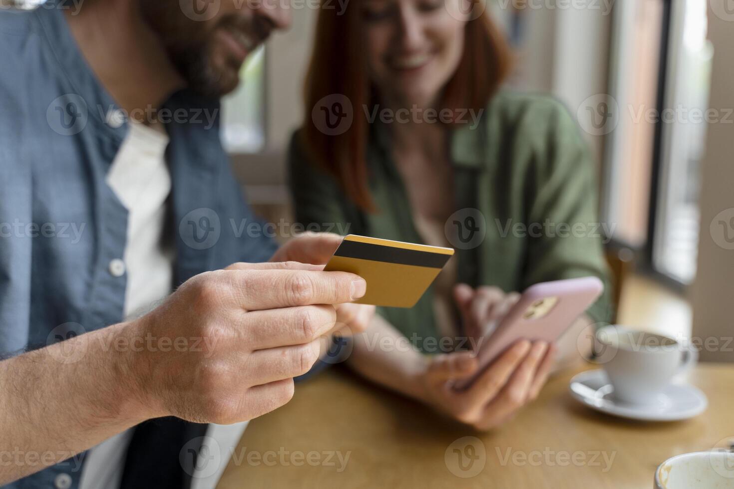 Couple smiling and making online payment holding credit card in cafe photo