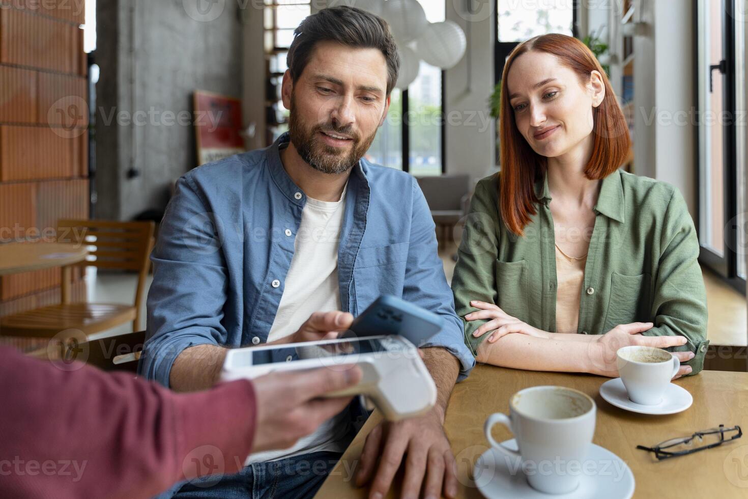 Couple making a contactless payment using a smartphone in a cafe photo