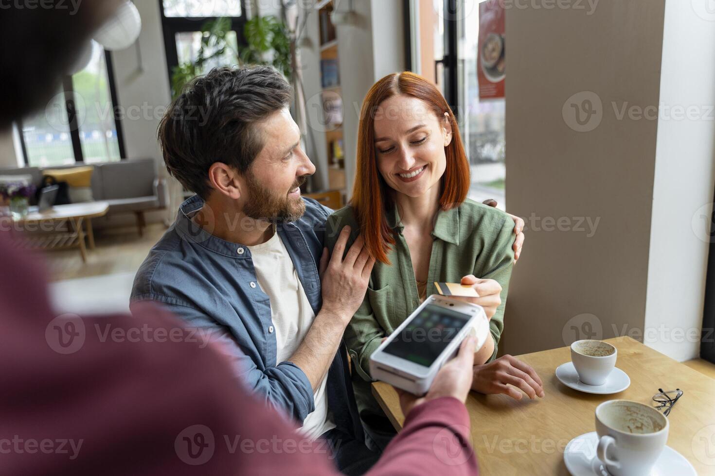 Happy couple making a card payment in a cafe photo