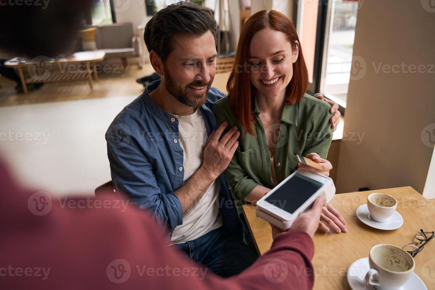 Happy couple making a payment using a credit card in a cafe photo