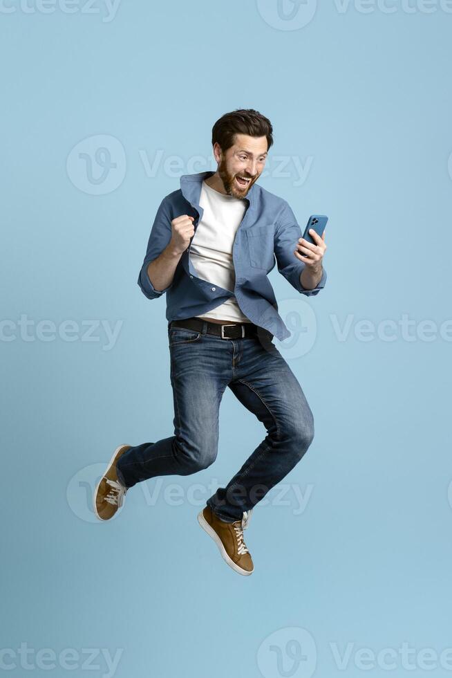 Excited man jumping and cheering reading good news on smartphone photo