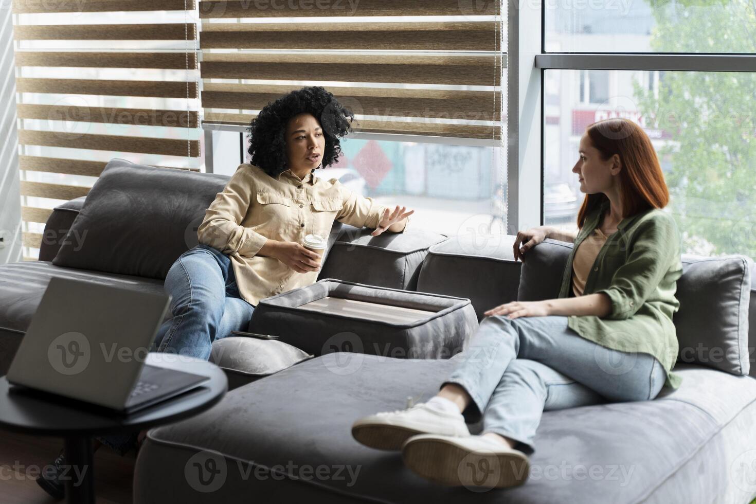 Two female colleagues relaxing and talking during break time in the office photo