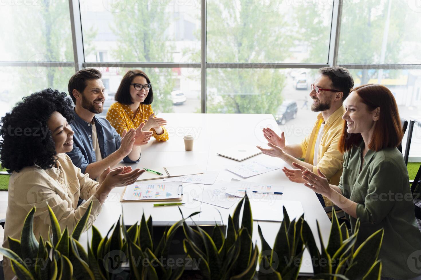 Diverse business team clapping after successful brainstorming meeting photo