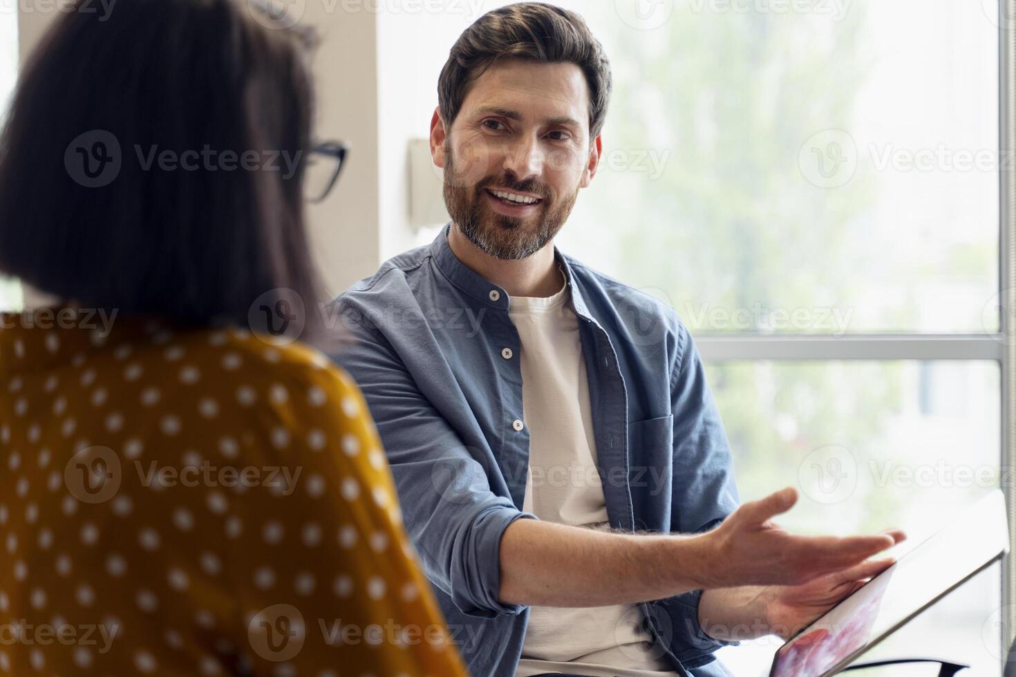 Smiling businessman showing digital tablet to female colleague during meeting photo
