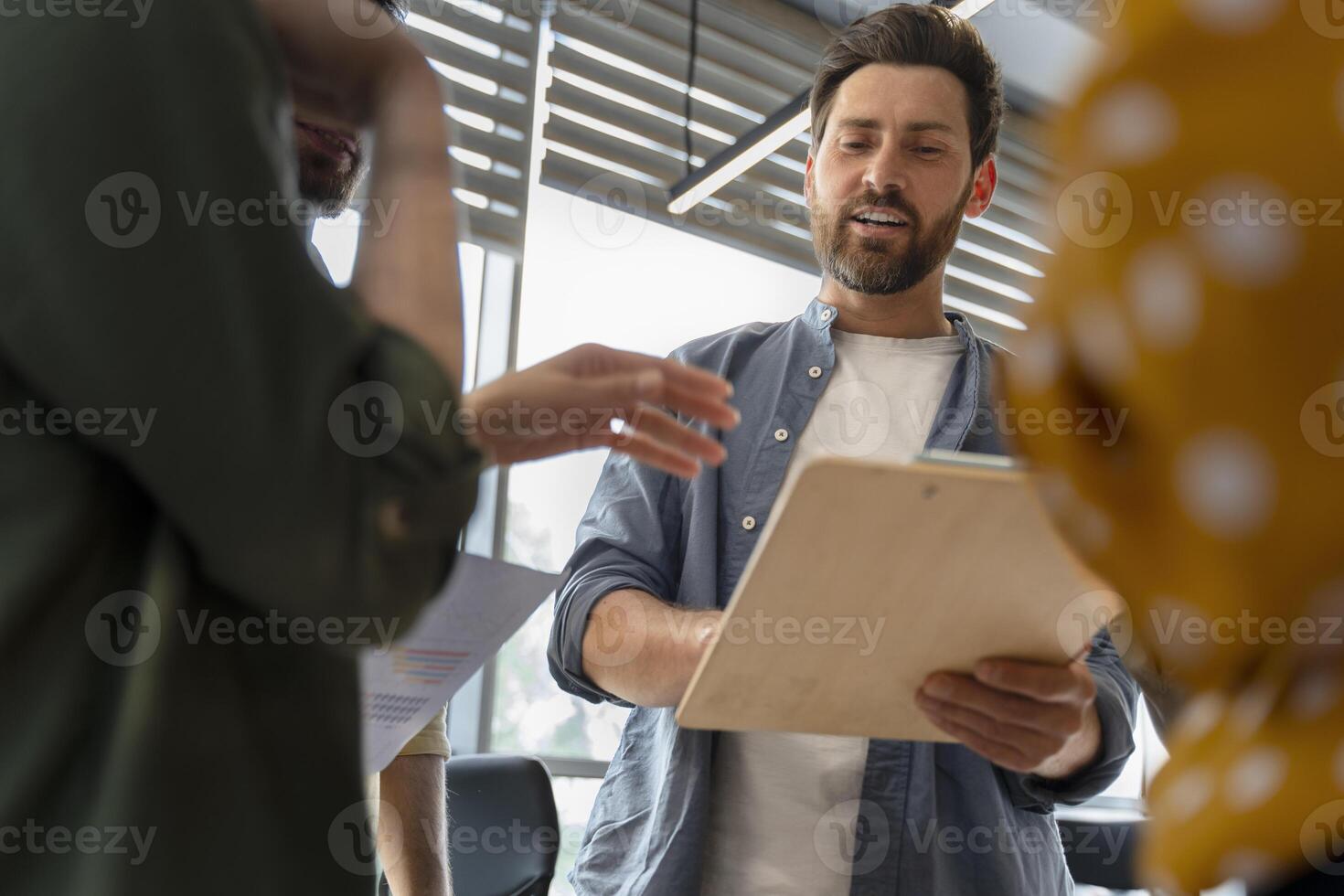 Manager holding meeting with creative team discussing project on clipboard photo