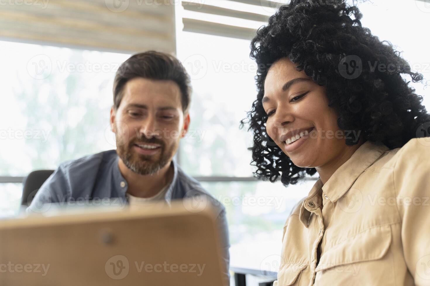Two colleagues smiling and working together on a project in the office photo