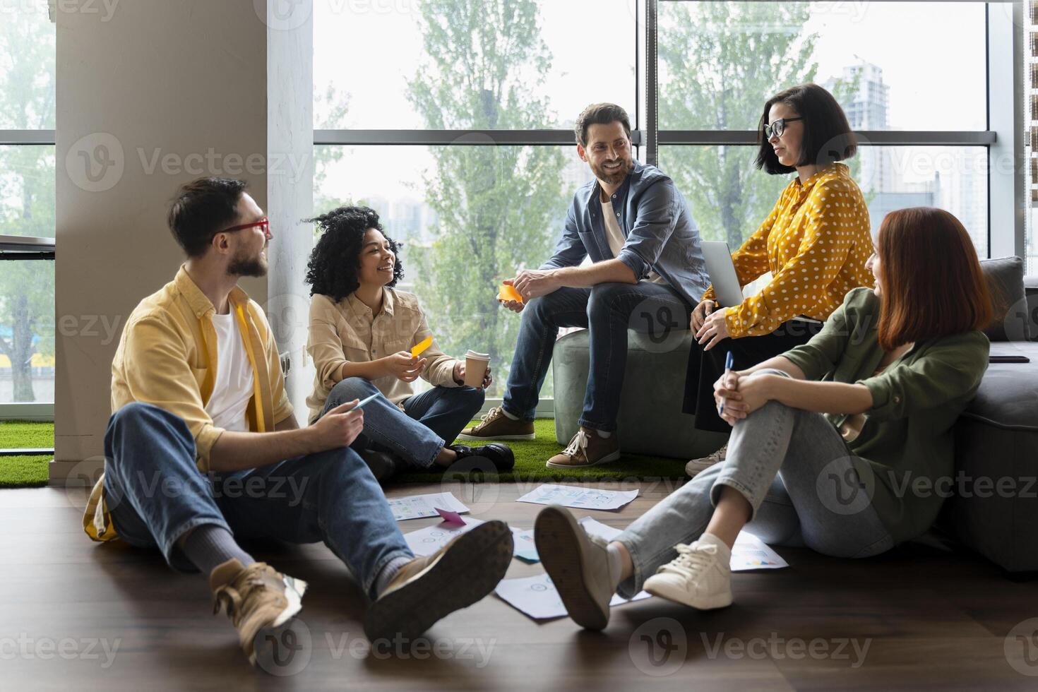 Diverse team of professionals brainstorming, sitting on the floor in the office photo