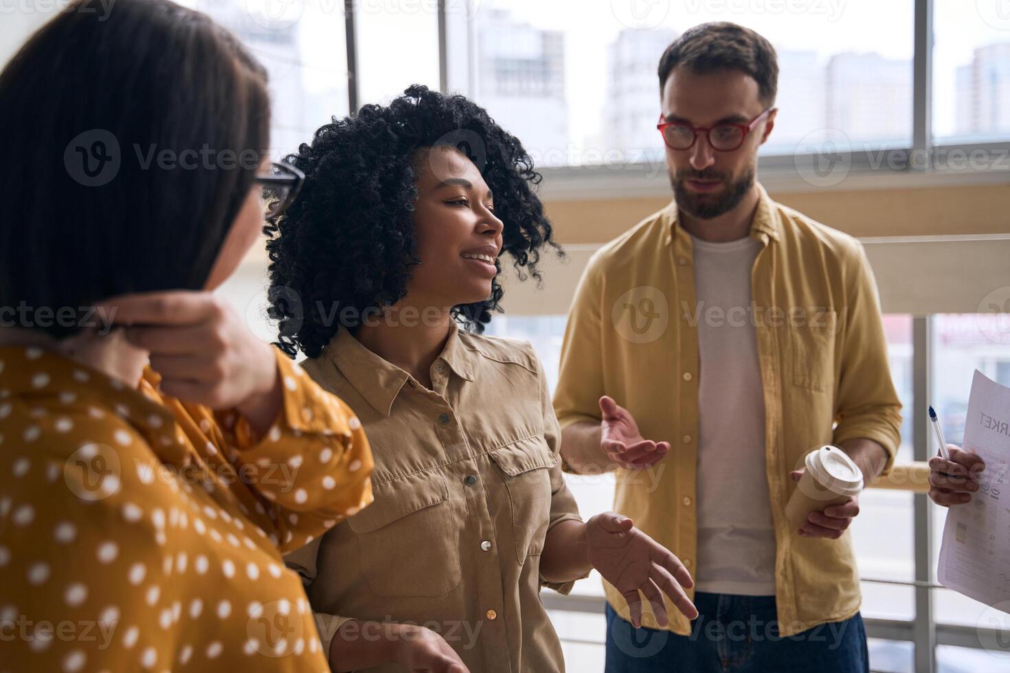 Group of young professionals having conversation during break in modern office photo