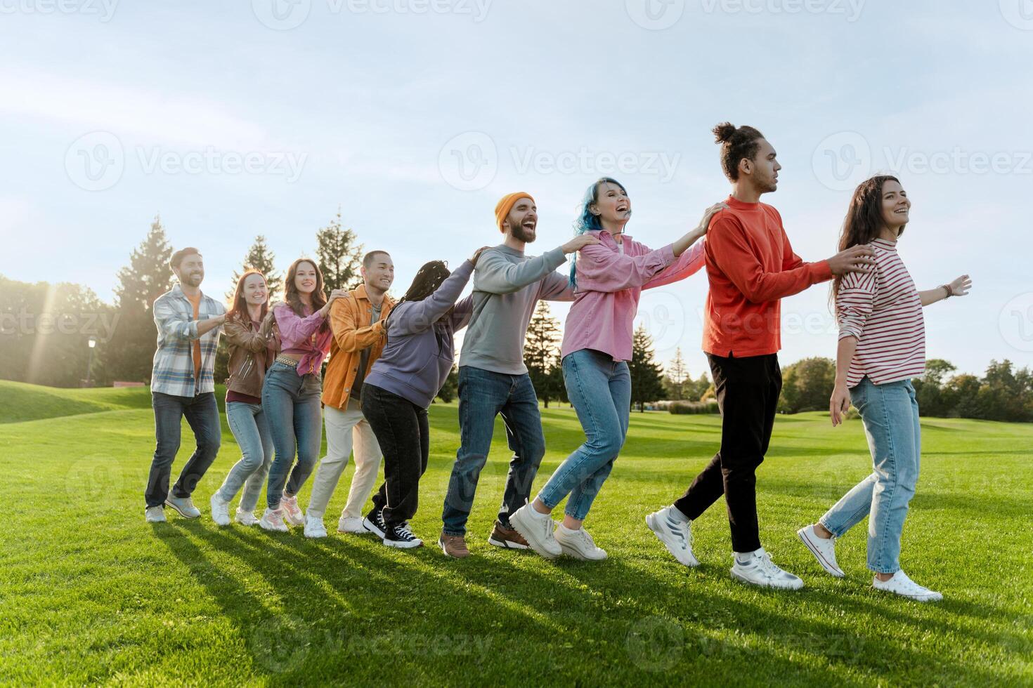 Group of diverse people holding hands and walking in line in park photo